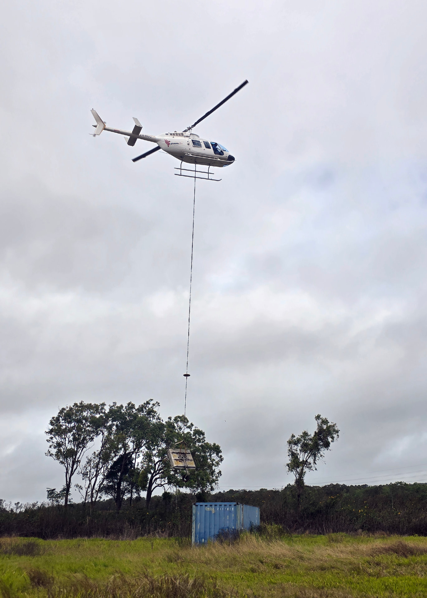 Phoenix Aero Niugini helicopter placing a slung load on site